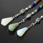 Three crystal pendulums, white, green, and opal, with Buddha head charms and beaded necklaces.