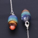Multi-stone pendulum necklace with different colored stones and metal chain.