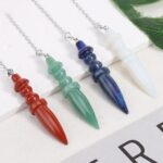 Four gemstone pendulums, red, green, blue, and white, on silver chains.