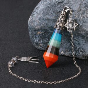Multi-colored gemstone pendulum with chain and charm, layered crystals.