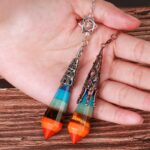 Multicolored gemstone pendulums with metal accents.  Two  pendants,  layered with  different colored stones, one teal/blue and one orange/brown.