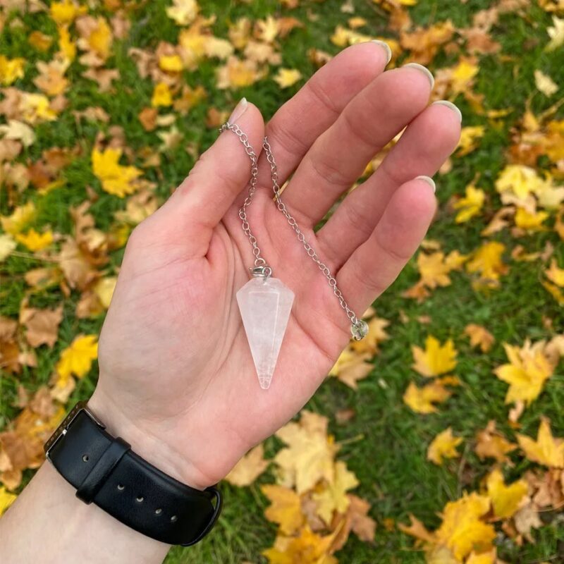 Rose quartz pendulum, held in hand, with chain.
