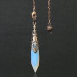 Light blue opal pendulum with ornate copper-colored metal accents.