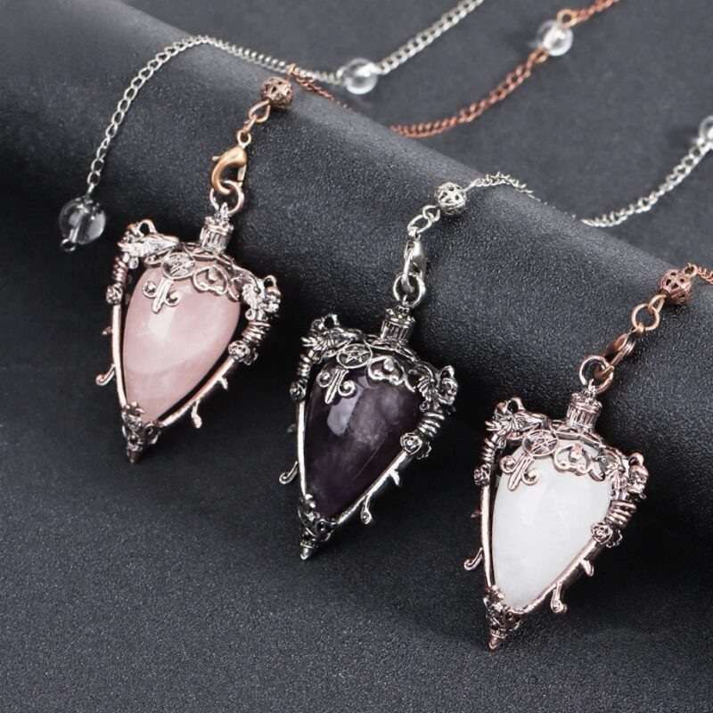 Three crystal pendulums, rose quartz, amethyst, and white, ornate metal frames.