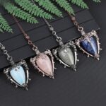 Four crystal pendulum pendents, rose quartz,  blue-gray, light blue, and lapis lazuli,  with ornate silver-tone settings.