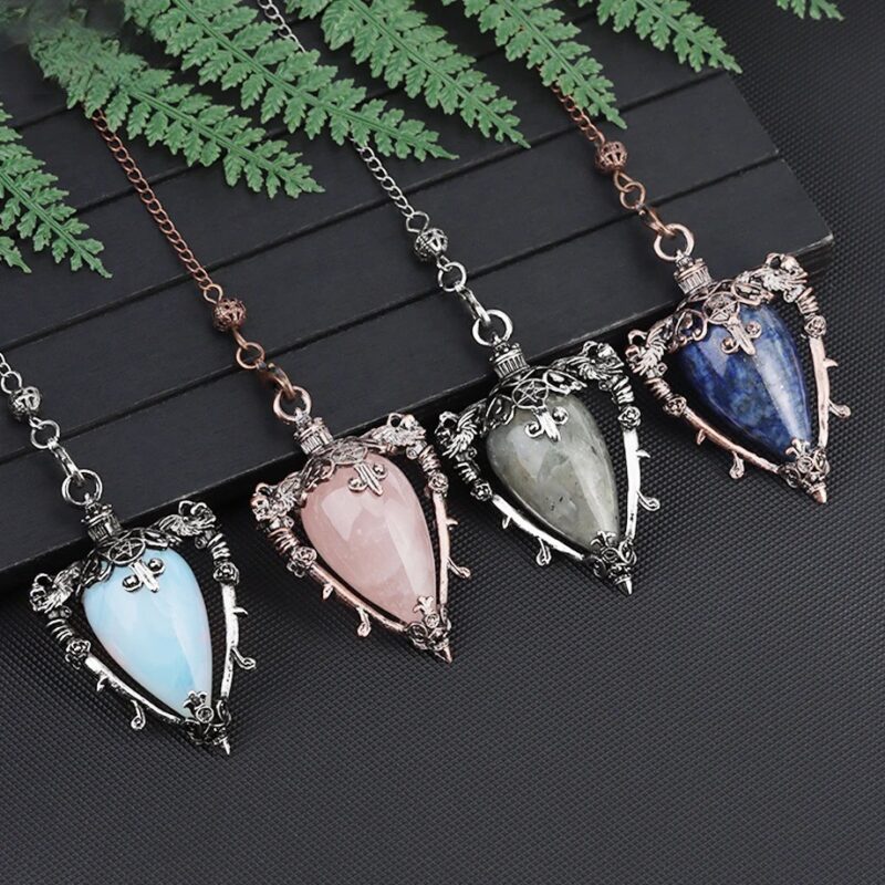 Four crystal pendulum pendents, rose quartz,  blue-gray, light blue, and lapis lazuli,  with ornate silver-tone settings.