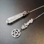 Clear quartz pendulum with metal accents and small crystals.