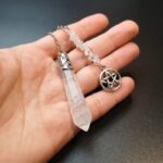 Clear quartz pendulum with metal accents and pentagram charm.