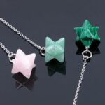 Two gemstone star pendulums, one rose quartz and one green aventurine, on silver chains.