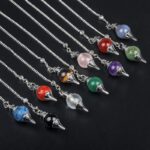 Assorted gemstone pendulums with metal chains.