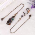 Two gemstone pendulums, one with amethyst, the other clear quartz, wrapped in copper wire with various colored stones.  Copper chain links.