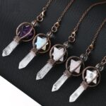 Four crystal pendulums, various colors, with quartz points and decorative metal settings.