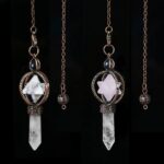 Three crystal pendulums, one with white, one with rose quartz, and one clear quartz, each with a metal star design.