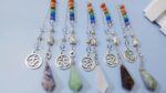 Multicolored gemstone pendulums with om symbols and buddha heads.  Healing crystals.