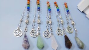 Multicolored gemstone pendulums with om symbols and buddha heads.  Healing crystals.