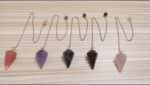 Set of 5 gemstone pendulums with various colors.  Rose quartz, amethyst, black spotted, tiger eye, and more.