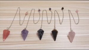 Set of 5 gemstone pendulums with various colors.  Rose quartz, amethyst, black spotted, tiger eye, and more.