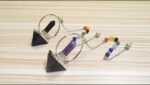 Two crystal pendulums, one with a black and one with a purple stone,  with a rainbow chakra bead chain.