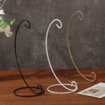 Three metal display stands, black, white, and gold, for decorative items.