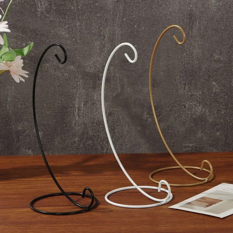 Three metal display stands, black, white, and gold, for decorative items.