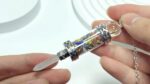 Crystal pendulum necklace, multi-colored stones in glass tube, silver accents.