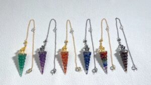 Colorful gemstone pendulums on chains.