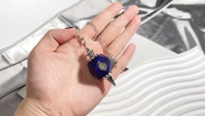 Blue lapis lazuli crystal pendulum with metal chain.
