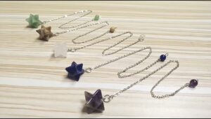 Assorted star-shaped crystal pendulums with chains.