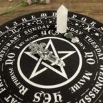 Black and white tarot or oracle board with crystals, pentagram, and days of the week.