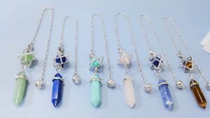 Set of crystal pendulums, various colors,  with metal chain, star and crystal point pendants.