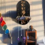 Black wooden wall-mounted display, moon phases design, crystals, pendulums.