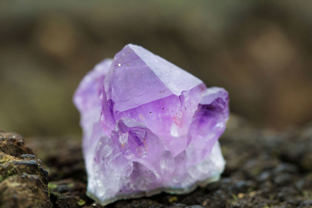 Close-up of amethyst crystal cluster on dark surface.