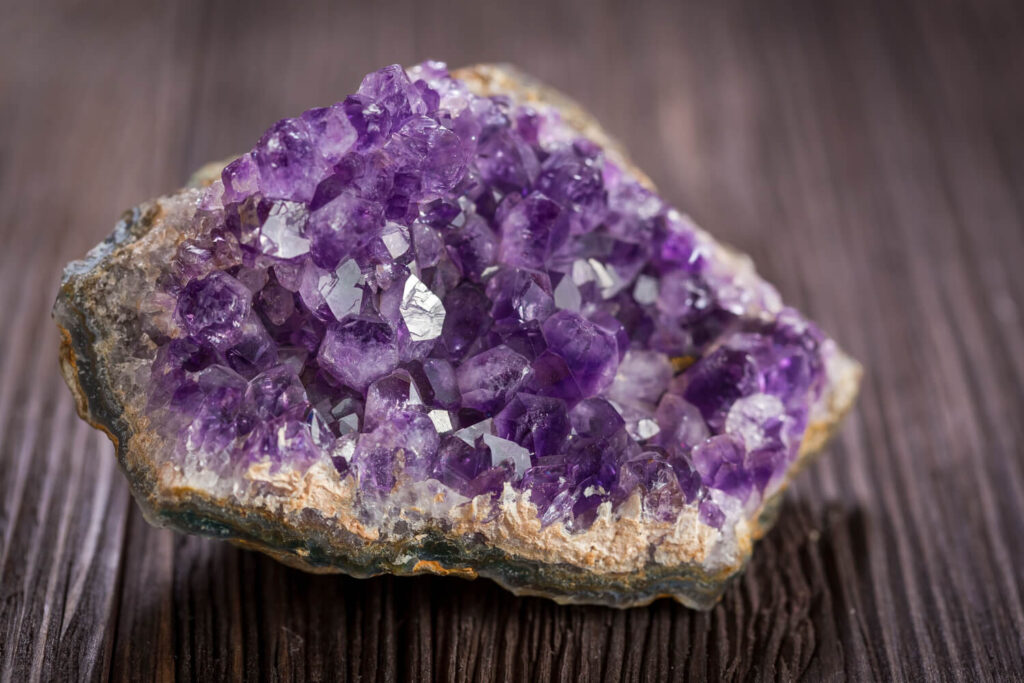 Purple amethyst cluster on dark wood.