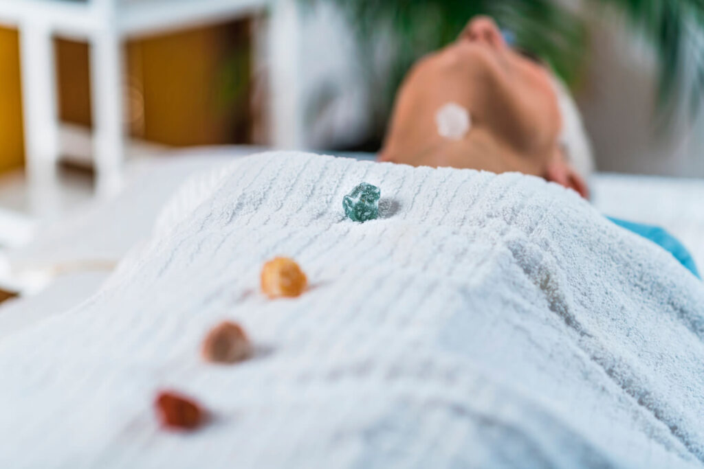 Person on spa table, crystals on white towel.