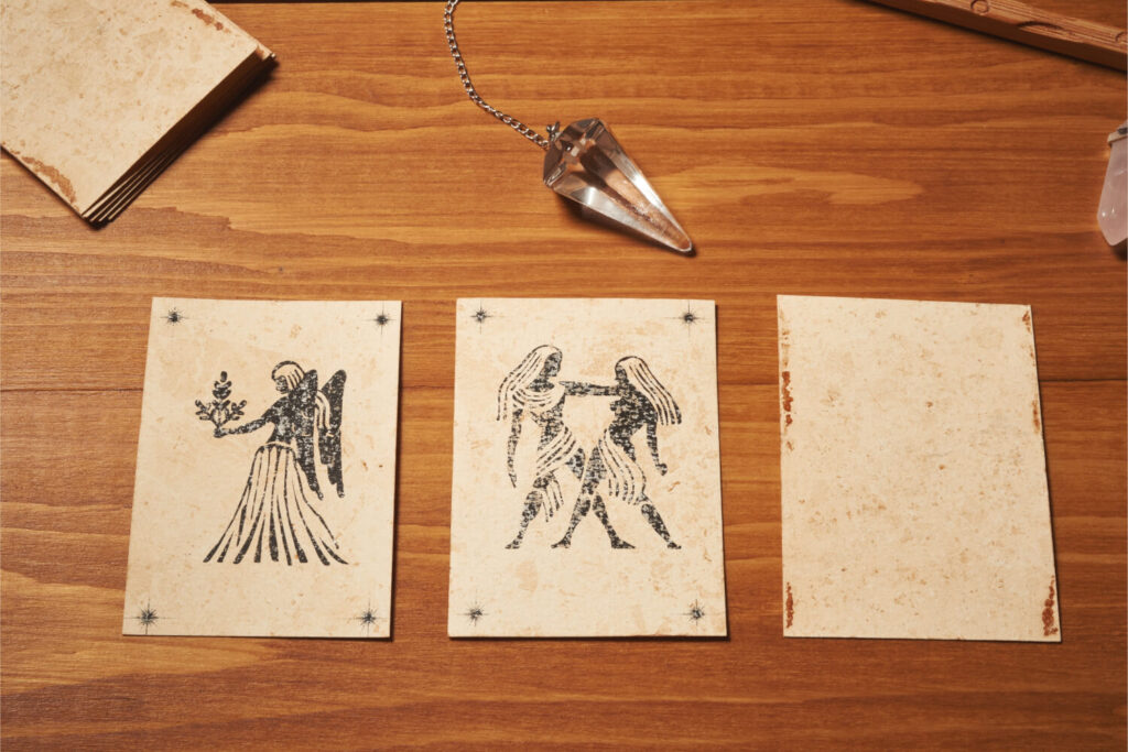 Zodiac cards, crystal pendulum, wooden surface.  Tarot, astrology, divination.