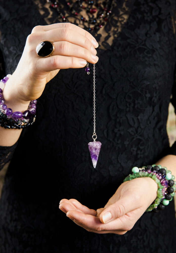 Woman holding amethyst pendulum.