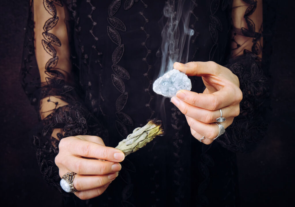 Woman holding a crystal and smudging stick.  Spiritual practice.