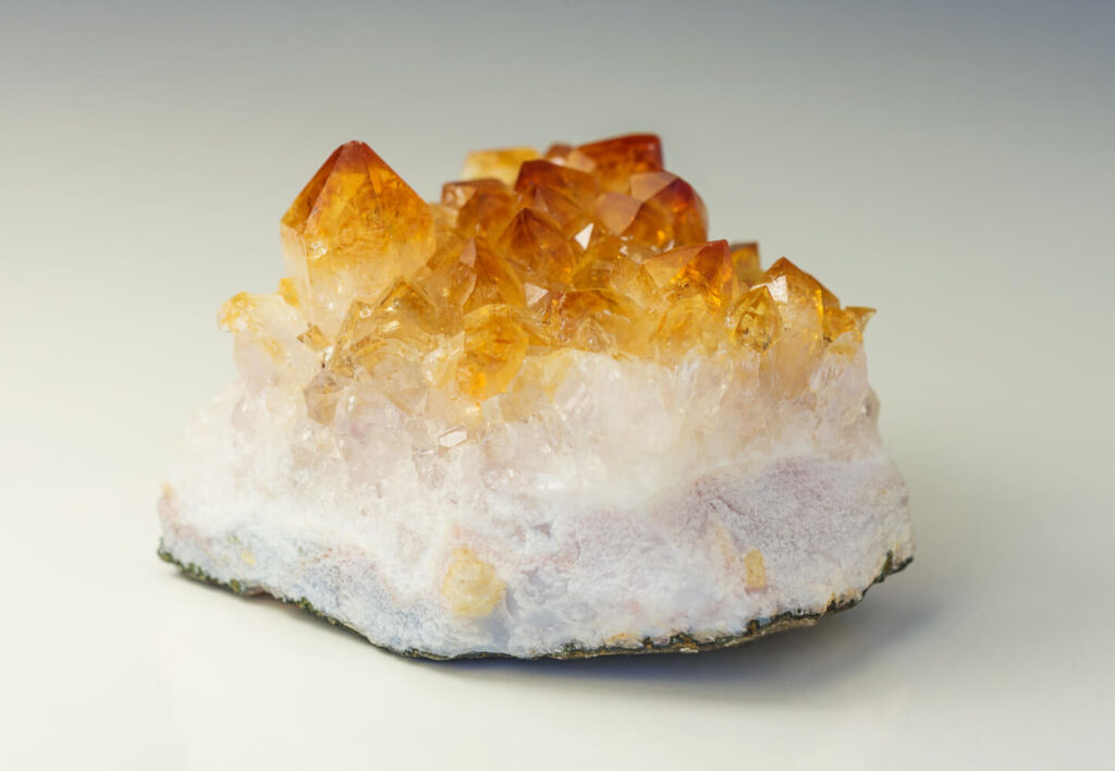 Close-up of a cluster of orange-yellow crystals on a white mineral base.