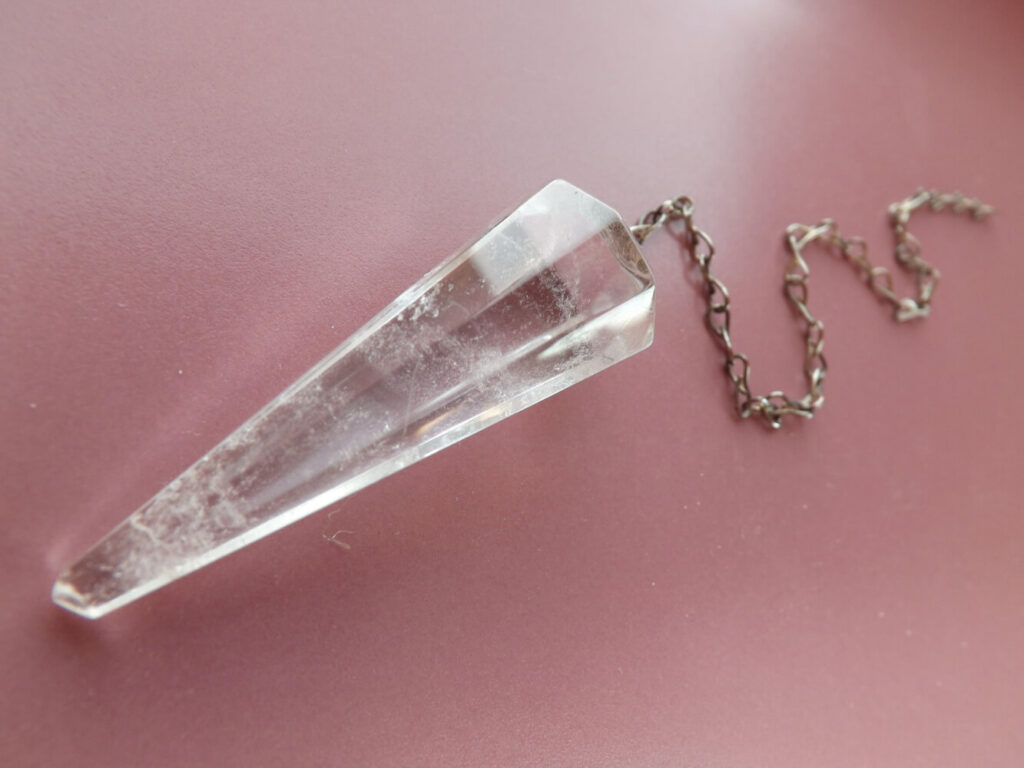 Clear quartz pendulum with metal chain.