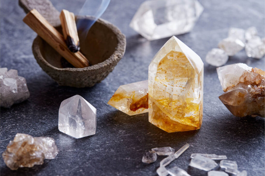 Crystals, palo santo, spiritual stones on dark surface.