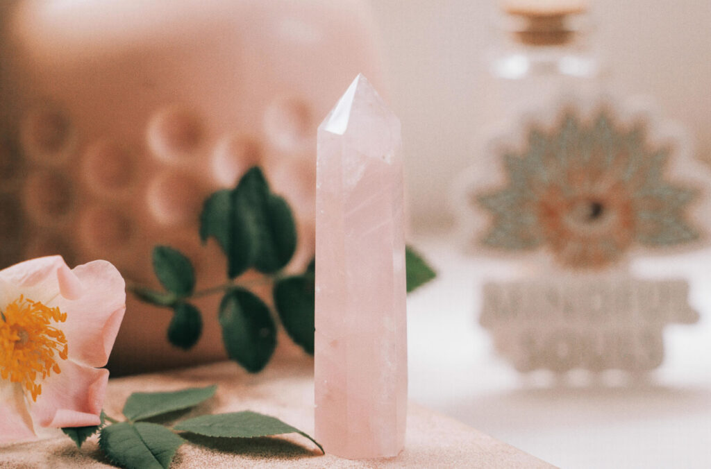 Pink quartz crystal point, rose flower, leaves.  Healing crystal.