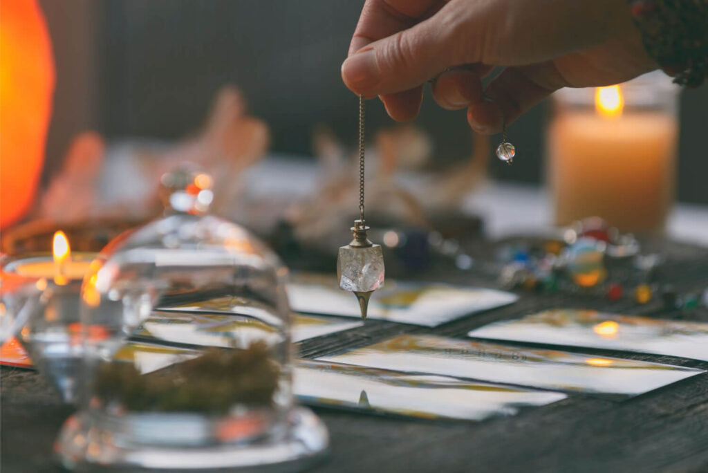 Tarot cards, pendulum, and crystals on a table.  Spiritual reading session.