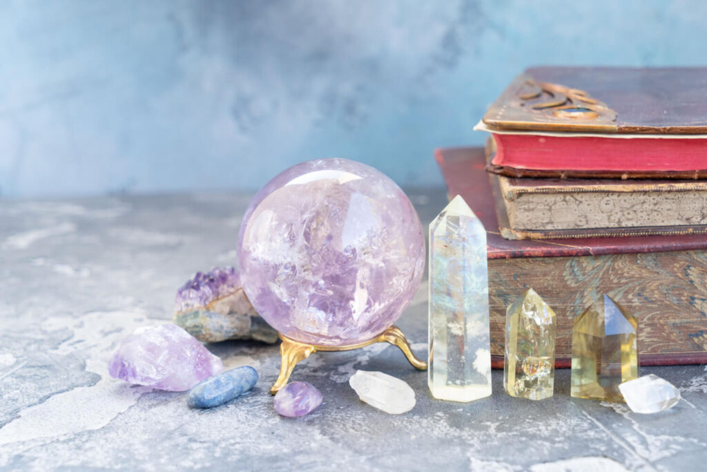 Amethyst crystal ball, quartz points, and other crystals, with vintage books.  Spiritual, healing crystals.