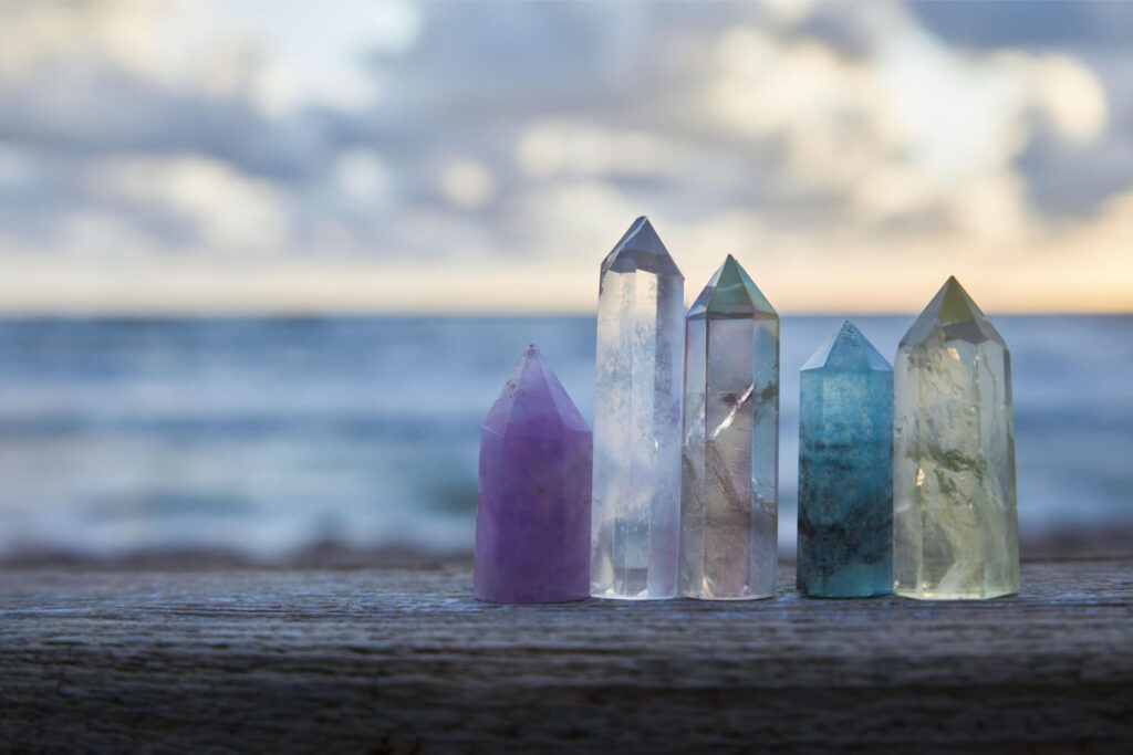 Colorful crystals on a wooden surface, ocean backdrop.