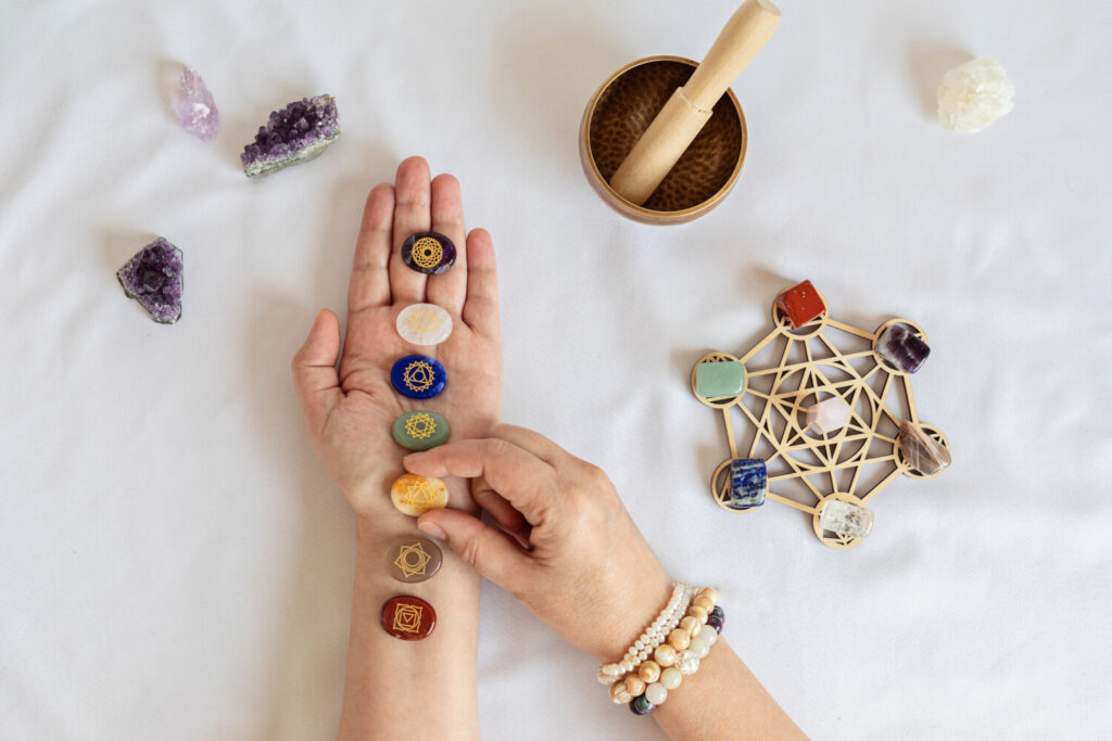 Seven chakra stones aligned on hand,  with a crystal grid and healing stones.  Alternative medicine.
