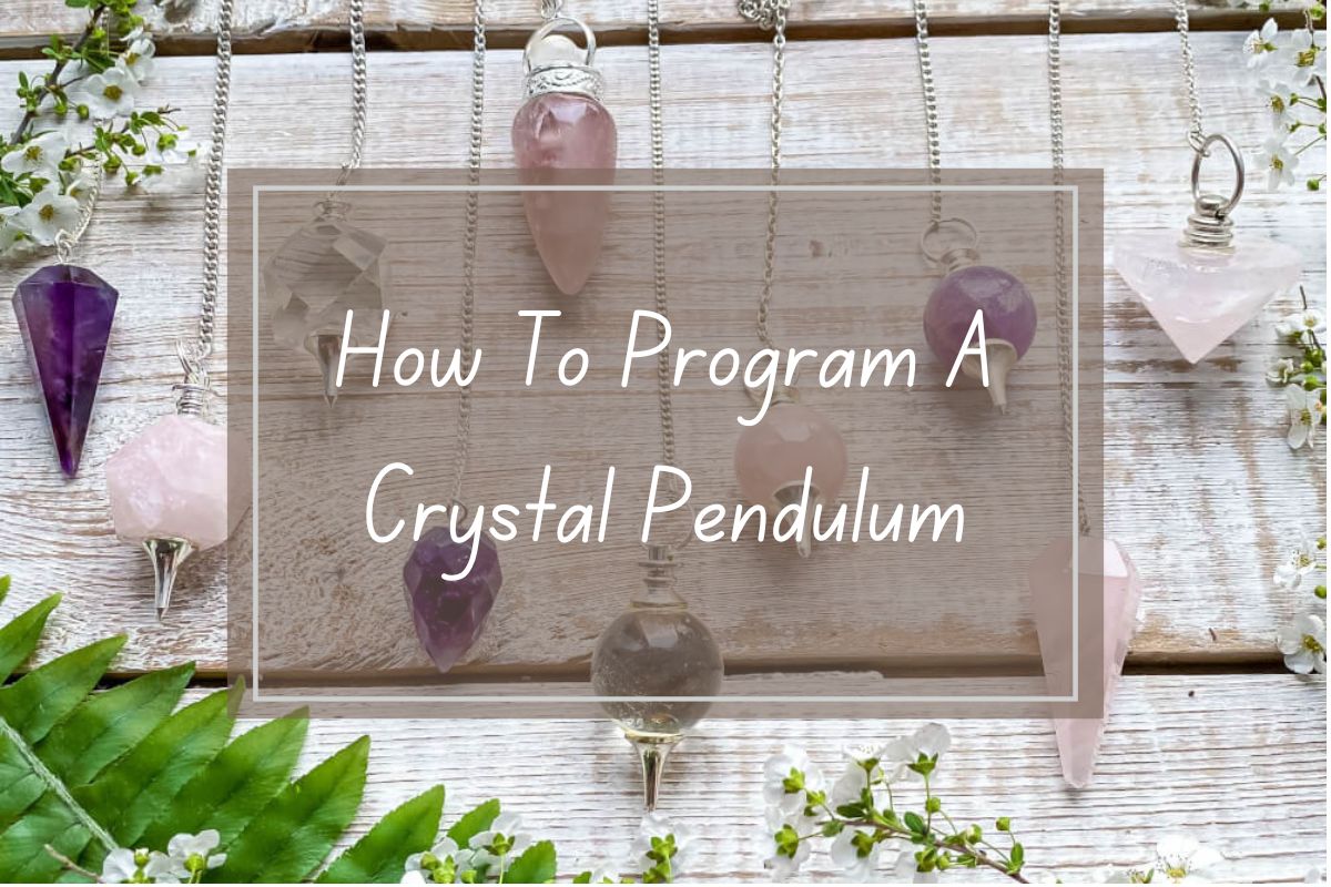 Crystal pendulums, various colors and shapes, displayed on a light wooden surface.  How to program a crystal pendulum title.