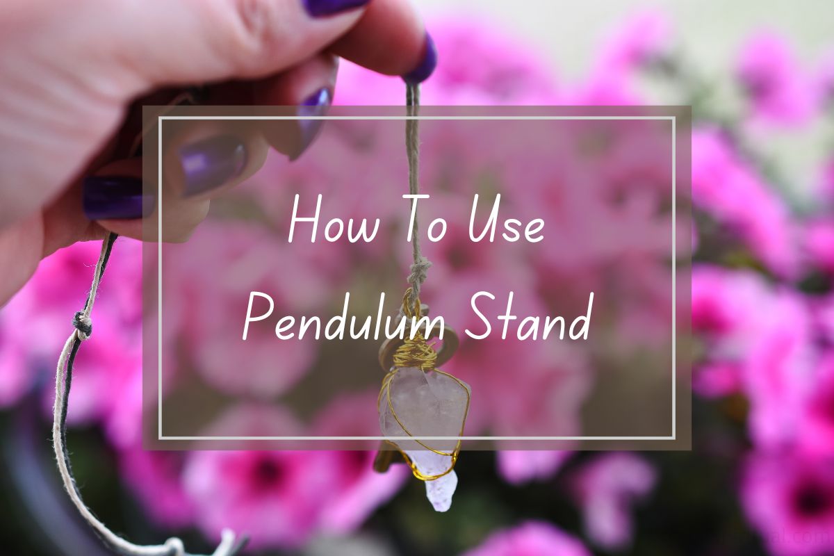Hand holding pendulum stand, how to use. Pink flowers background.