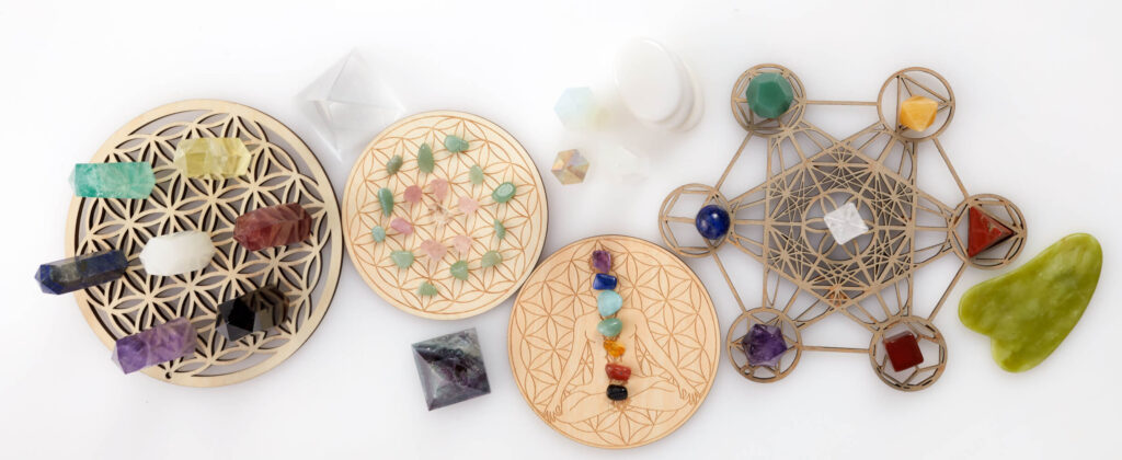 Various colorful crystals and stones, arranged on wooden flower of life and Merkaba-like stands.  Healing stones.