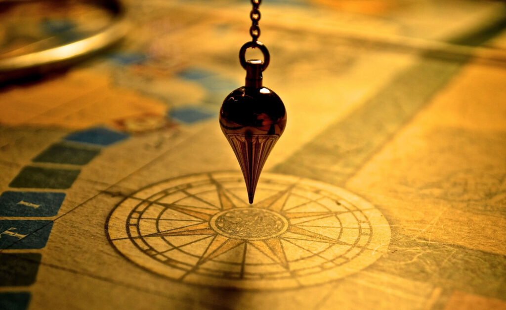Antique pendulum over compass rose on aged paper.