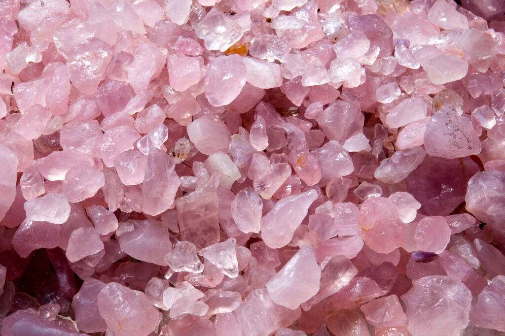 Close-up of many small, pink, raw quartz crystals.